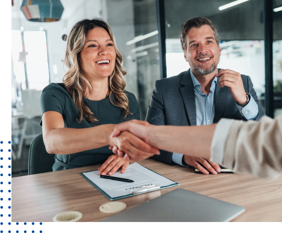 Handshake at a business meeting, smiling colleagues.