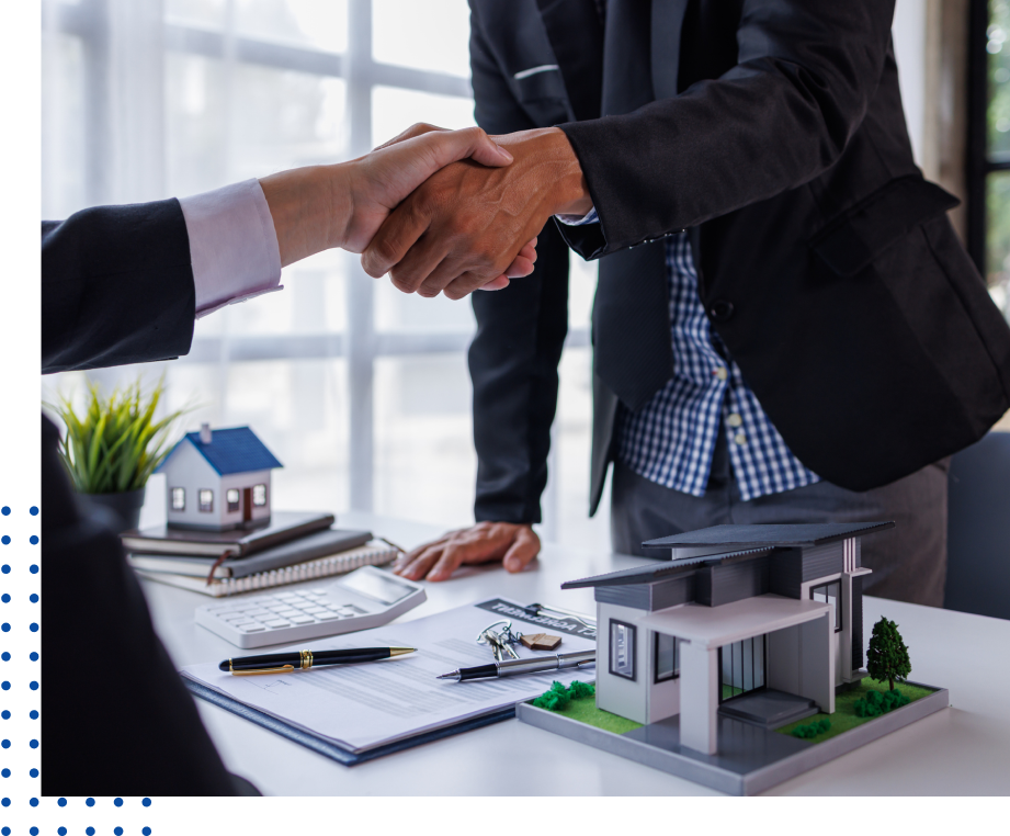 Handshake over real estate documents and models.